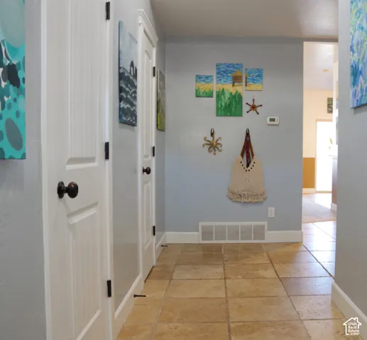 Hallway featuring tile flooring, smooth-finish walls, and multi-panel interior doors with dark hardware