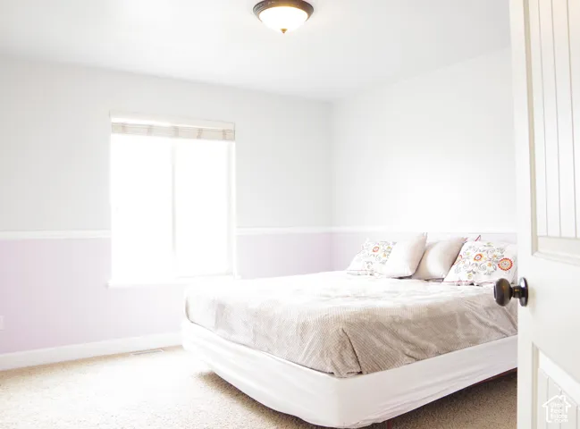 Room featuring two-tone wall paint with a chair rail, neutral wall-to-wall carpeting, a sliding window with a built-in shade, and a flush-mount ceiling light fixture