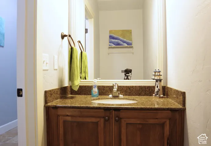 Bathroom vanity with stone-surface countertop, integrated undermount sink, warm-tone wood cabinetry, and large wall-mounted mirror with decorative frame