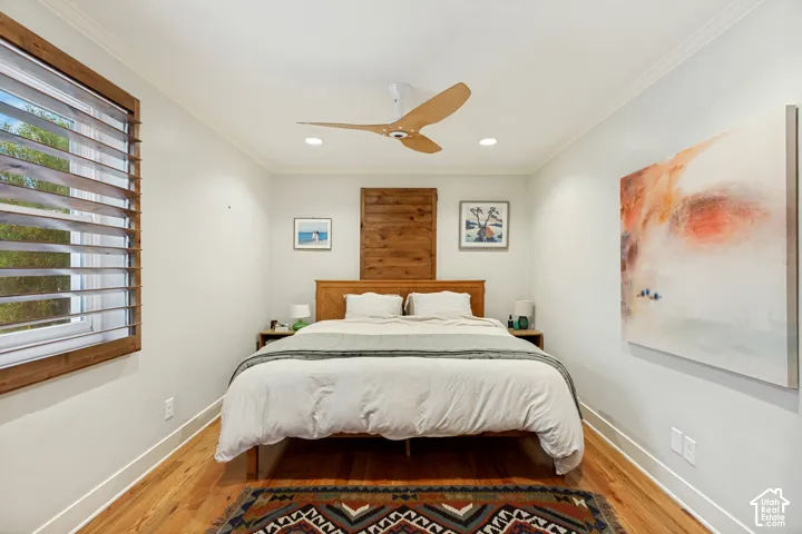 Wood-finish flooring, recessed lighting, three-blade ceiling fan, and window featuring wood-trim casing