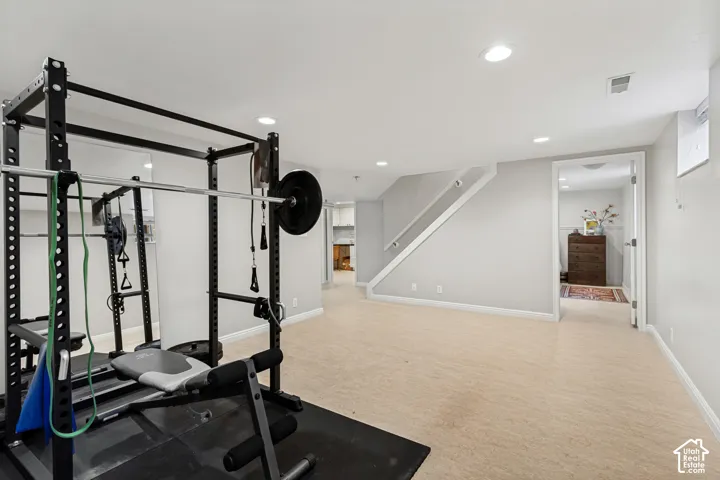 Finished interior space with recessed lighting, neutral wall paint, carpeted flooring, and a staircase featuring a white handrail