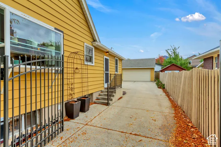Horizontal lap siding exterior, concrete driveway, detached garage, metal gate, and wood-slat fencing
