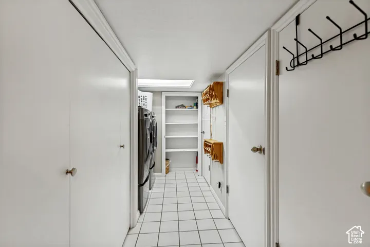 Utility area featuring white tiled flooring, recessed ceiling lighting, built-in shelving, and dual floor-to-ceiling closets