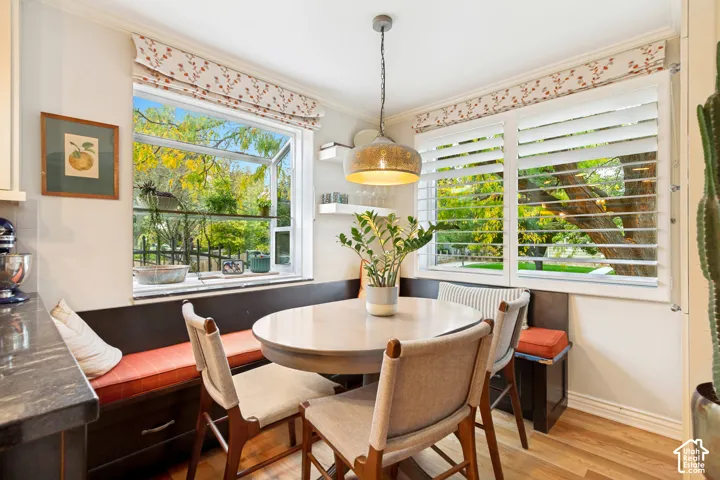 Built-in corner bench seating with integrated storage drawers, casement window, plantation shutters, metal pendant lighting, and wood-finish flooring