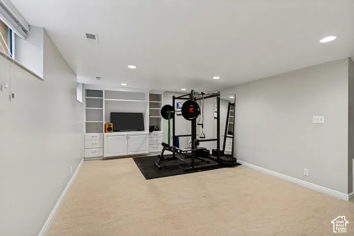 Neutral-toned interior featuring recessed lighting, built-in white cabinetry with open shelving, and carpeting