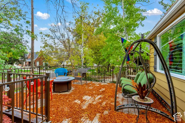 Elevated wooden deck featuring metal railings, integrated string lighting, and mature trees