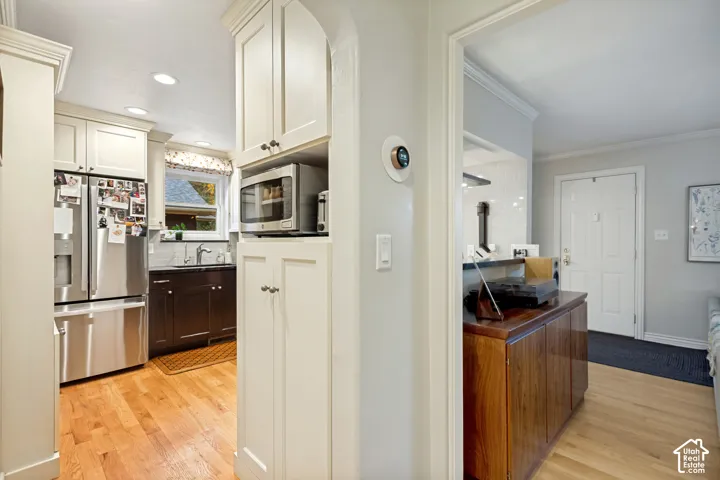 Kitchen featuring recessed lighting, light-toned cabinetry, stainless steel refrigerator, dark-toned lower cabinetry, and wood-finish flooring