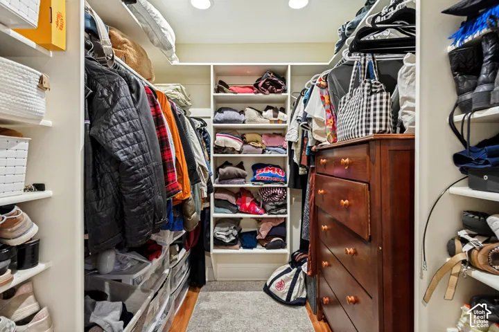 Walk-in closet featuring white built-in shelving, adjustable storage racks, and recessed ceiling lighting