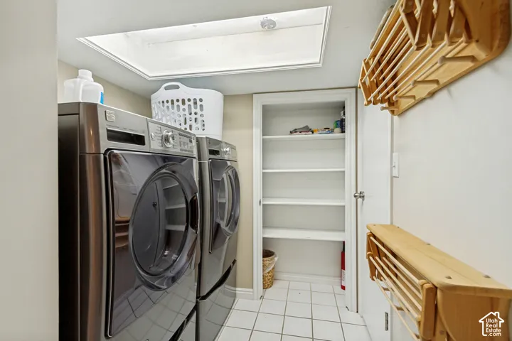 Laundry room featuring a skylight, ceramic tile flooring, built-in shelving, and wall-mounted wooden drying racks