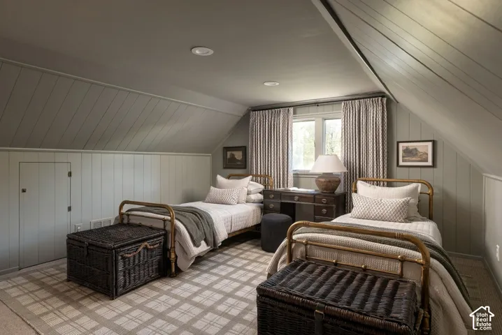 Sloped ceiling room featuring tongue-and-groove wall paneling, recessed lighting, and a built-in access panel