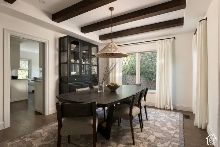 Dining area featuring exposed wooden ceiling beams, built-in dark cabinetry, and diamond-patterned window panes