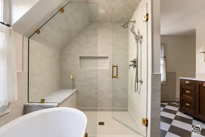 Walk-in shower featuring glass paneling, gold-tone hardware, a built-in stone-top bench, recessed shelving, and light-toned subway wall tile