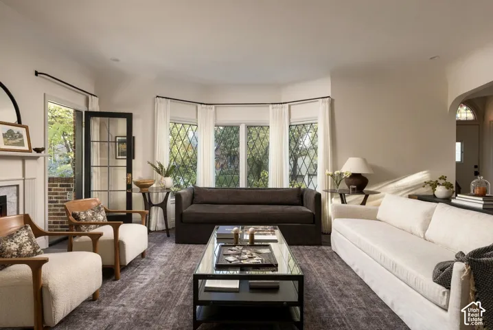 Living room featuring a bay window with diamond-pane glass, arched entryway, and a fireplace with a decorative mantel