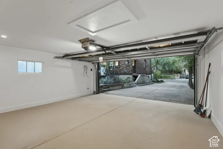 Finished garage interior with smooth walls, ceiling access panel, integrated lighting, and a concrete driveway