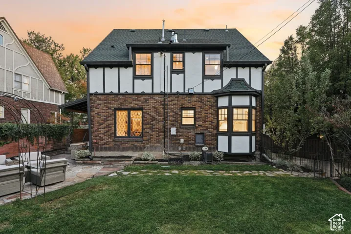 Tudor-style exterior featuring brick and half-timbered facade, multi-pane windows, a bay window, and stone hardscaping