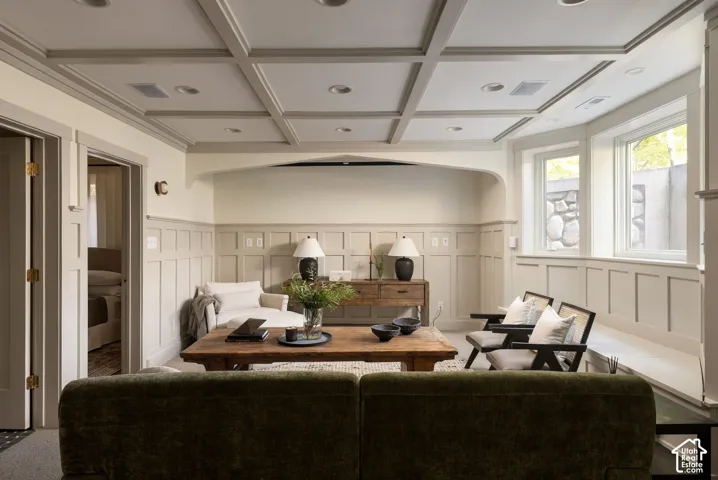 Coffered ceiling featuring recessed lighting, extensive wainscoting, arched architectural detail, and multi-pane windows
