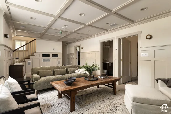 Coffered ceiling, extensive wall paneling, built-in staircase railing, and wall-mounted light fixtures