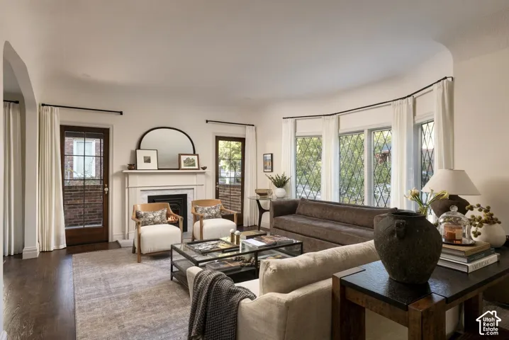 Living area featuring dark wood-finish flooring, a traditional fireplace with a classic mantel, and a multi-panel bay window with lattice-pattern glass