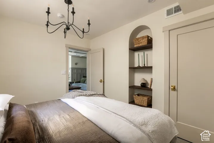 Arched recessed wall niche with three wood-finish shelves, matte black five-arm chandelier, and solid-core interior door with metallic hardware