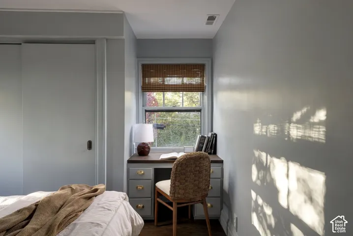 Built-in desk featuring a dark countertop, multi-drawer cabinetry, brass-tone hardware, and a single-pane window