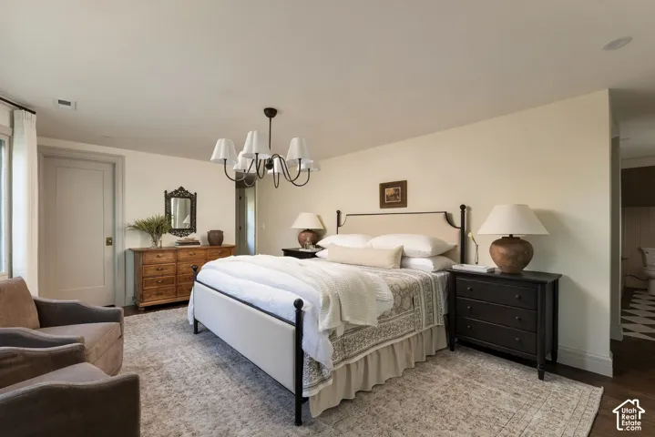 Neutral-toned walls, dark wood-finish flooring, and a multi-arm chandelier with fabric drum shades