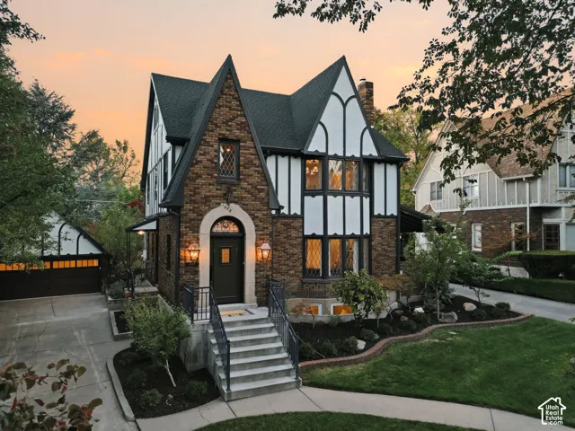 Tudor-style exterior featuring brick and half-timbered facade, arched stone entryway, steeply pitched rooflines, and leaded glass windows
