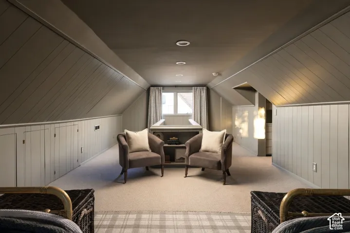 Vaulted ceiling with diagonal paneled wood walls, integrated built-in cabinetry, neutral carpeting, and recessed lighting
