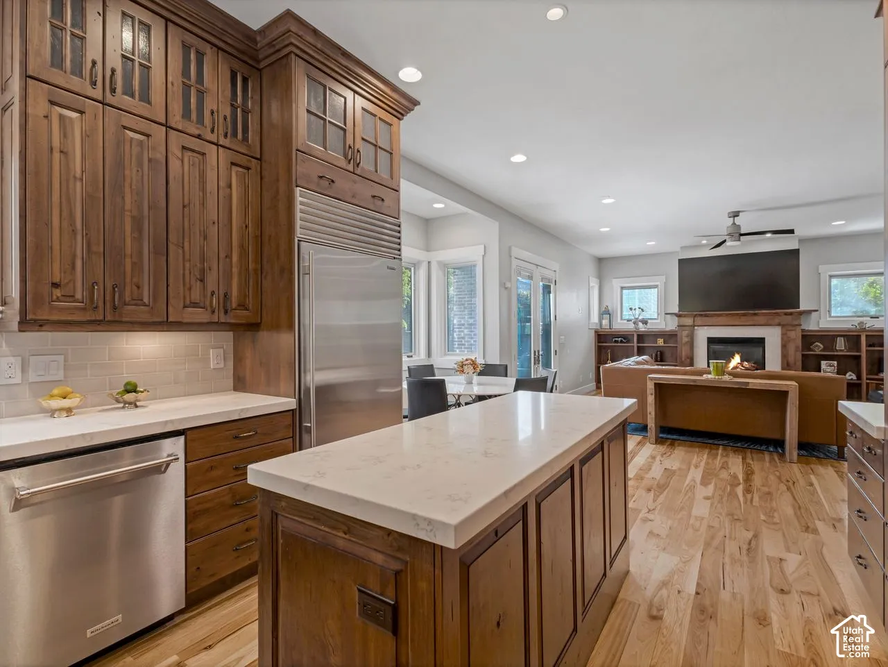 Kitchen featuring ceiling-height custom wood cabinetry, quartz countertops, a center island, stainless steel appliances, and wood-finish flooring
