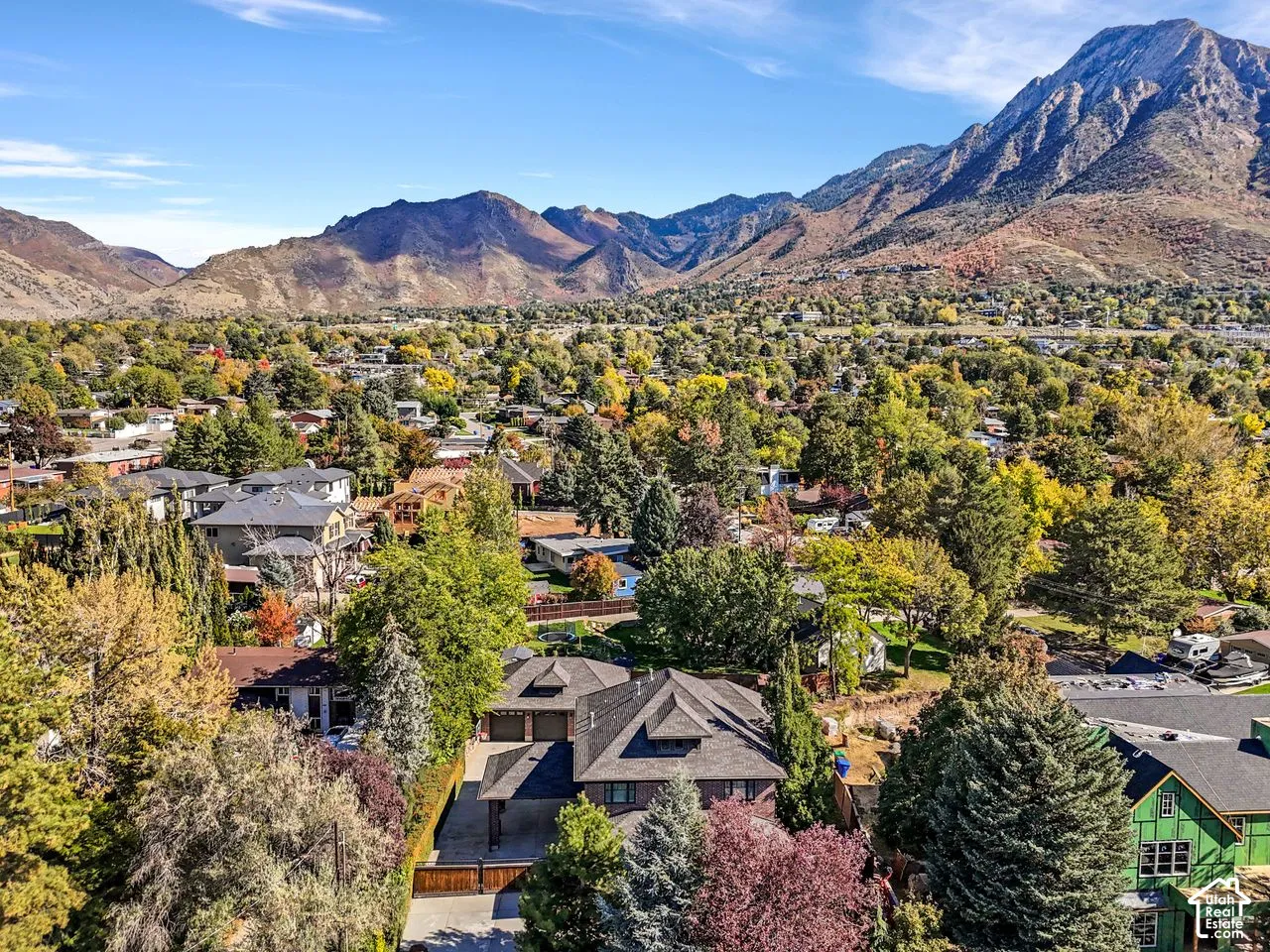 Aerial perspective of a multi-level residence featuring a multi-pitched roof, attached garage, and prominent mountain backdrop