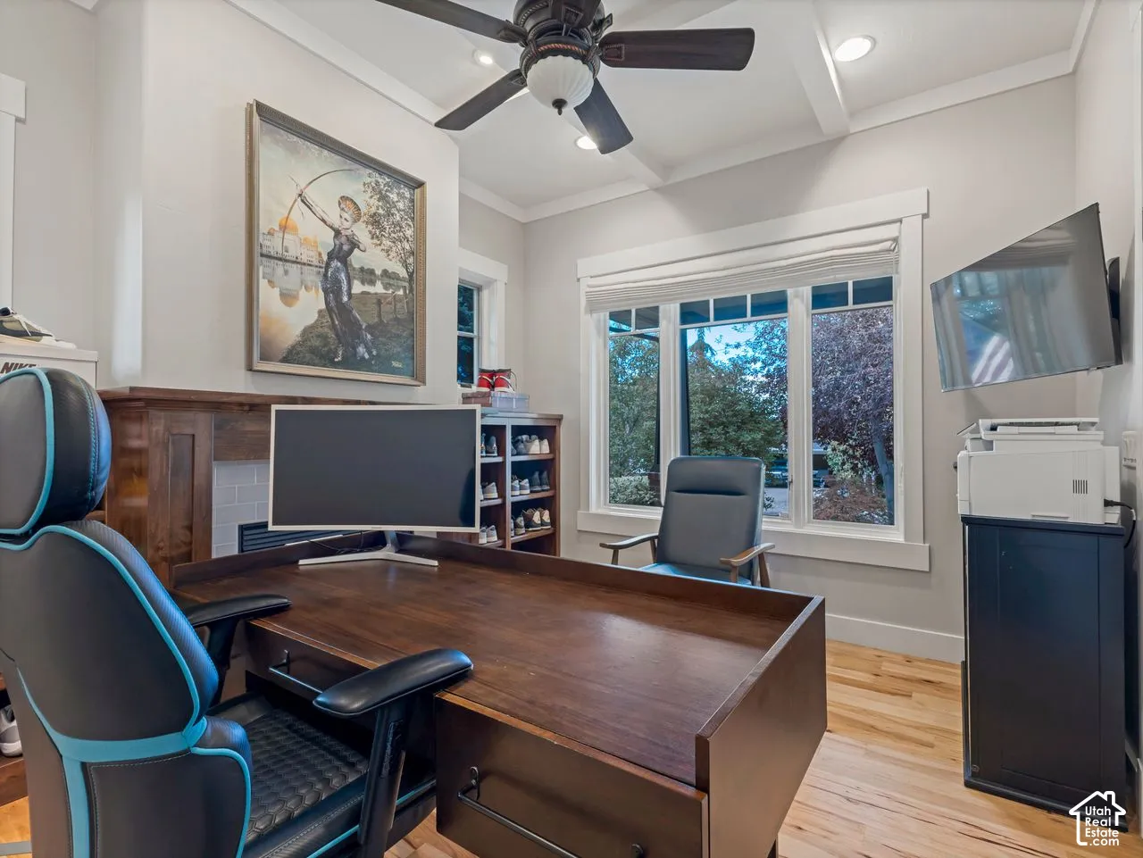 Wood-finish flooring, fireplace with a wood mantel, crown molding, multi-pane windows, and a ceiling fan