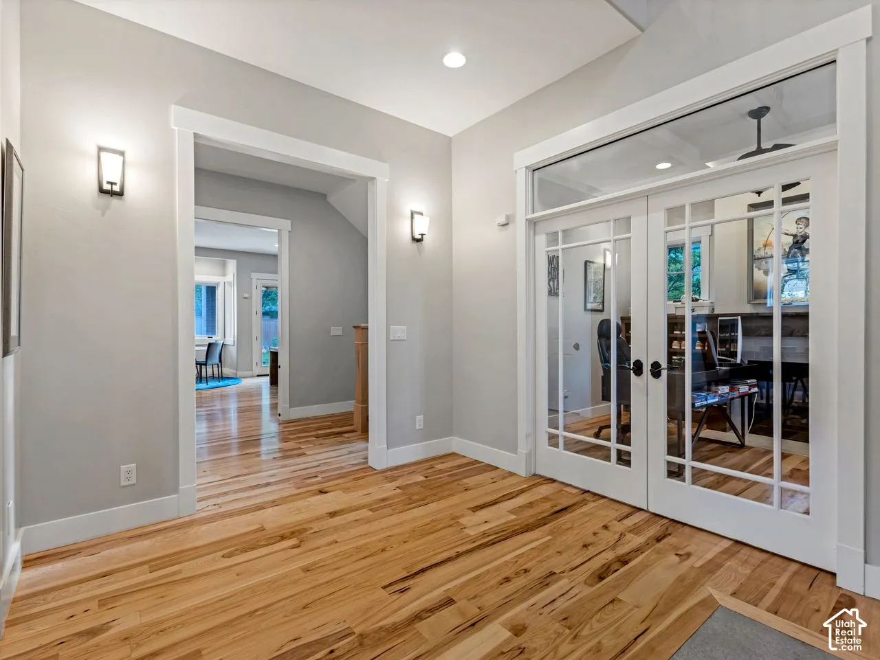 Entryway featuring wood-finish flooring, double French doors with glass panes and transom window, recessed ceiling lighting, and wall-mounted sconces