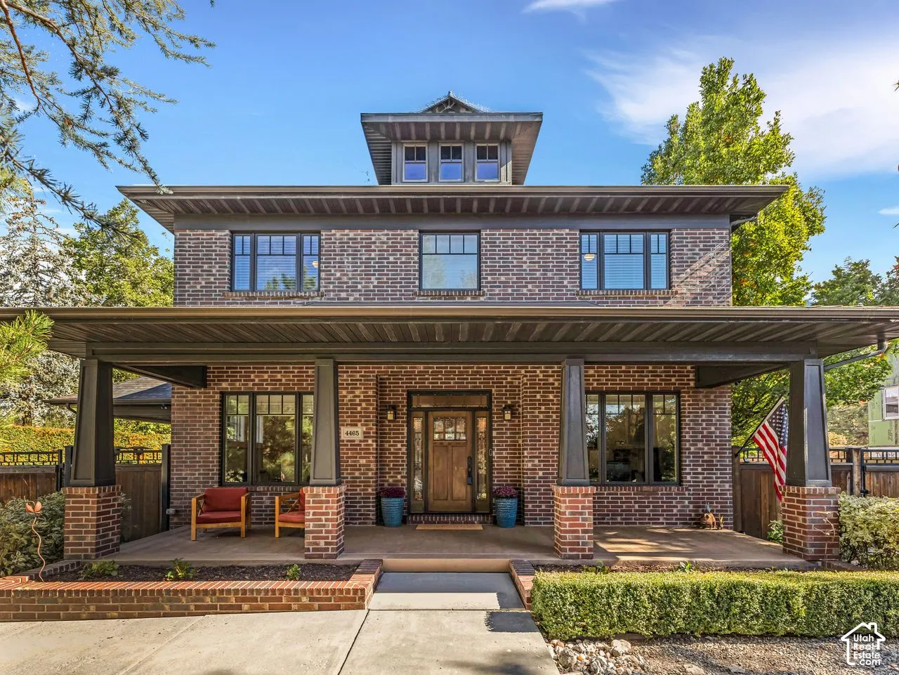 Two-story brick exterior featuring a covered front porch with tapered columns, a decorative roofline cupola, and a wooden front door with glass pane detailing