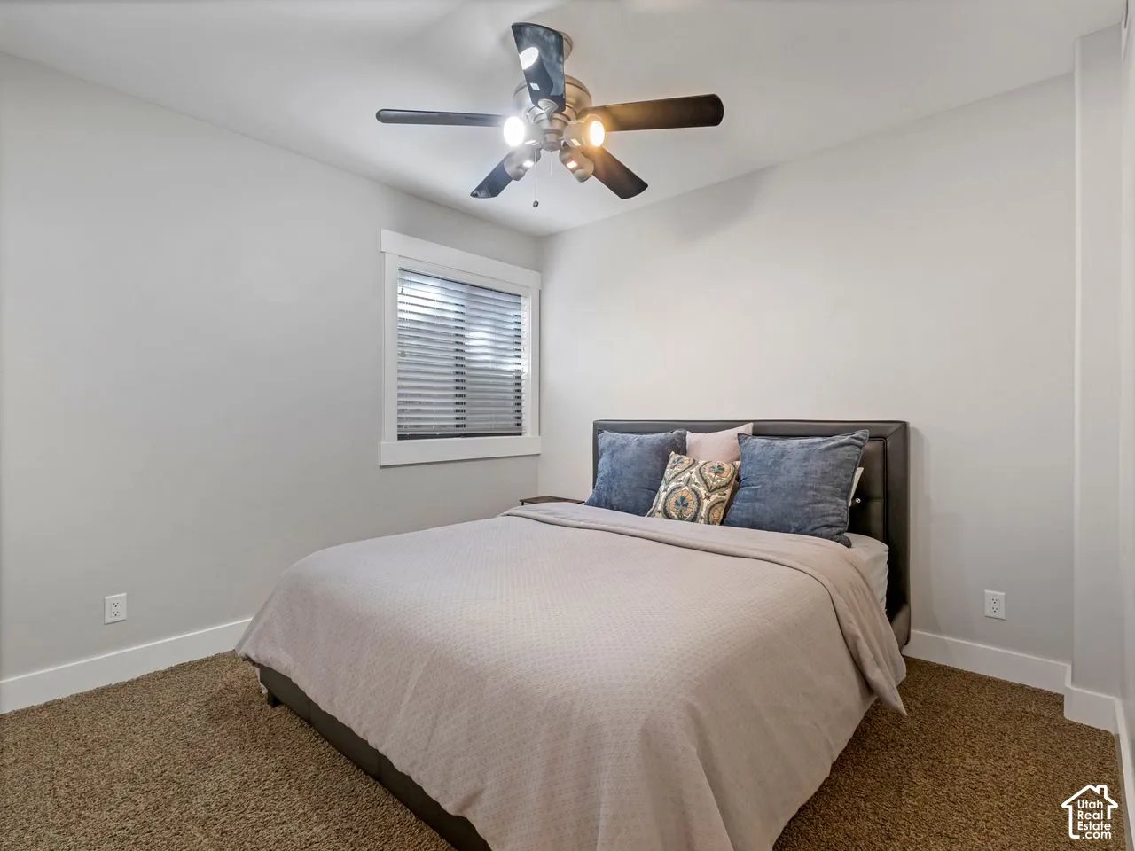 Neutral-toned walls, ceiling fan with integrated lighting, carpeted flooring, and window with casing and blind