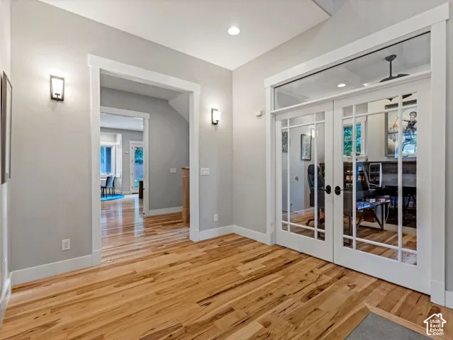 Entryway featuring wood-finish flooring, double French doors with glass panes and transom window, recessed ceiling lighting, and wall-mounted sconces
