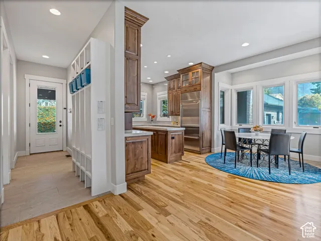 Kitchen featuring custom wood cabinetry, stainless steel panel-ready refrigerator, wood-finish flooring, and built-in mudroom storage with integrated shelving