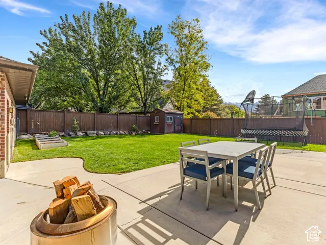 Backyard featuring a concrete patio, a manicured lawn, raised garden beds, a storage shed, and a full-perimeter privacy fence
