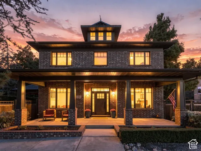 Craftsman-style exterior featuring red brick masonry, a covered front porch with tapered columns, a central cupola, and multi-pane windows