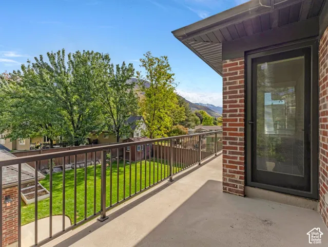 Second-story balcony featuring red brick exterior accents, a metal railing, and concrete flooring