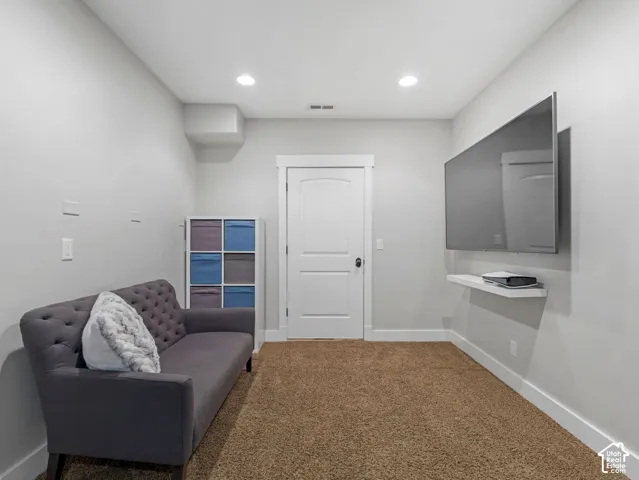 Interior room featuring neutral-toned carpeting, recessed ceiling lighting, a solid-core interior door with casing, and a wall-mounted floating shelf