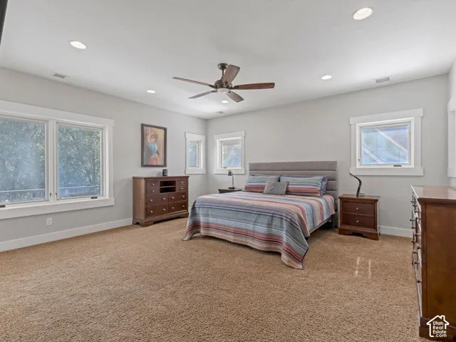 Spacious room featuring neutral wall tones, recessed lighting, carpeted flooring, a ceiling fan, and multi-pane windows