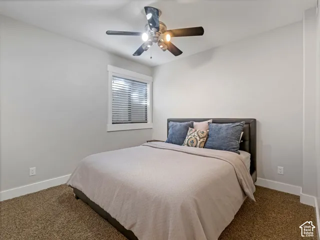 Neutral-toned walls, ceiling fan with integrated lighting, carpeted flooring, and window with casing and blind