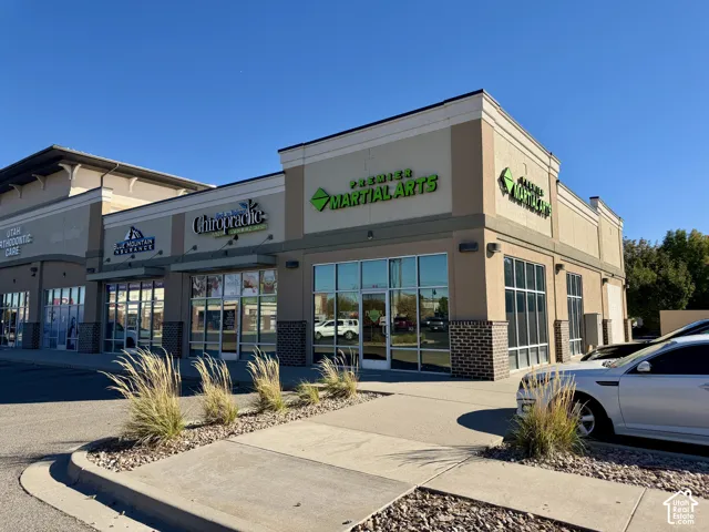 Commercial retail building facade featuring extensive glass storefronts, brick masonry accents, stucco exterior finish, and prominent corner unit signage positioning