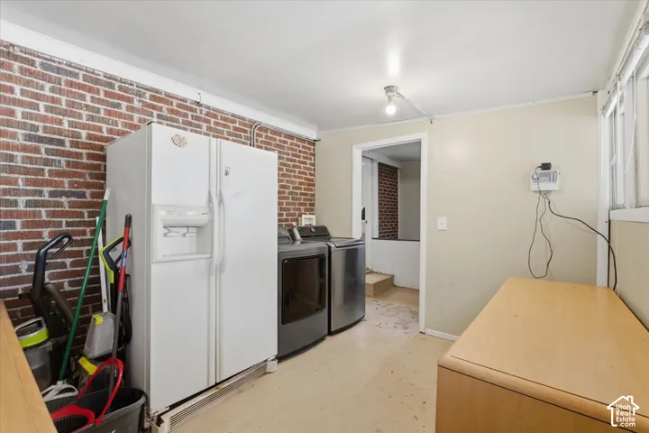 Utility space featuring a red brick accent wall and flat-finish ceiling