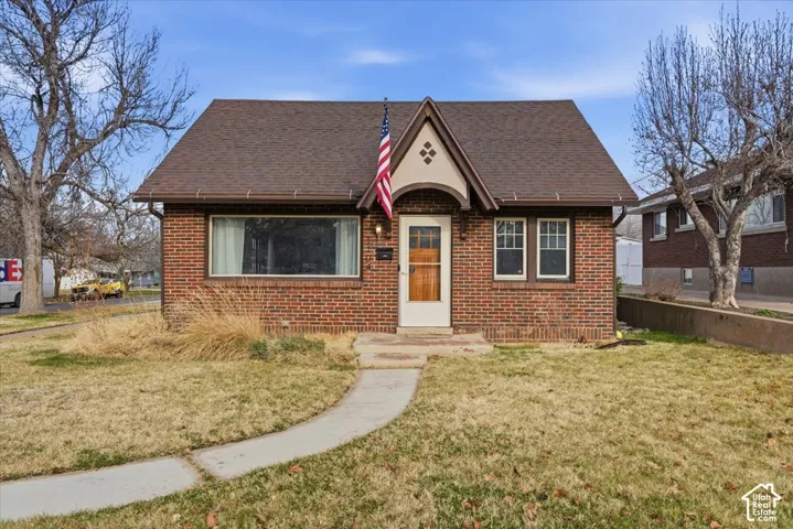 Brick exterior featuring a gabled roofline, a decorative front entryway arch, and a wood-finish front door