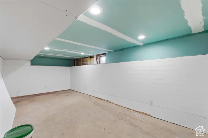 Unfinished interior space featuring white horizontal plank wall paneling, ceiling-mounted recessed lighting, and exposed drywall ceiling panels