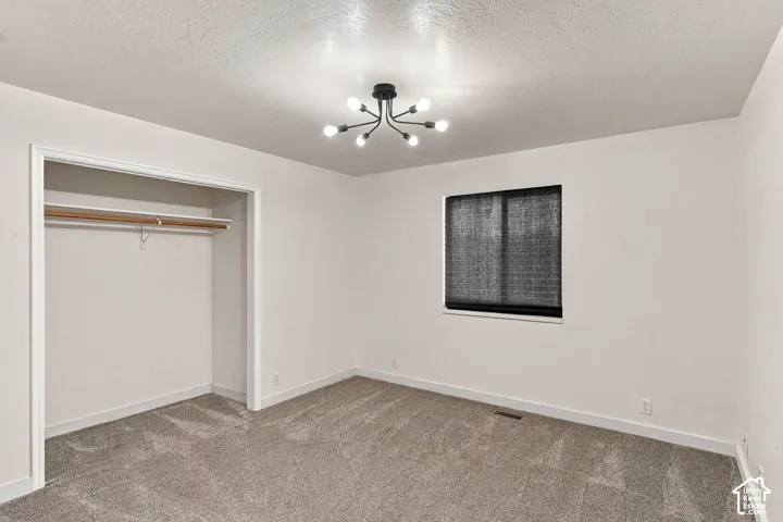 Neutral-toned carpeting, modern multi-arm chandelier, and built-in closet storage