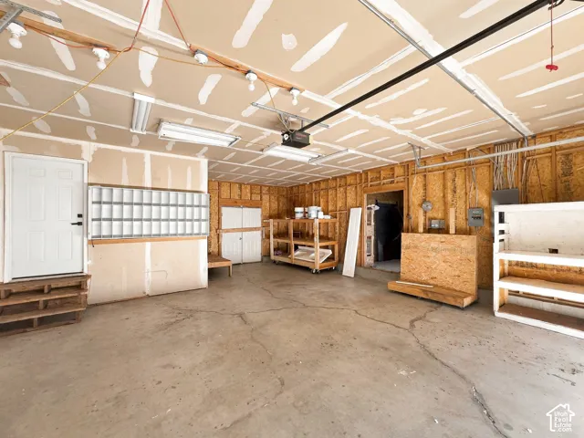 Multi-car garage featuring a concrete floor, overhead fluorescent lighting, and multiple built-in wooden storage units
