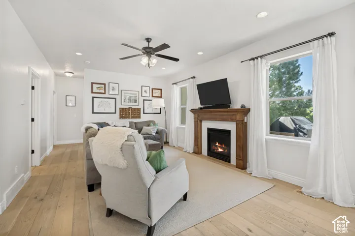 Living area featuring wood-finish flooring, a fireplace with a wood mantle, recessed lighting, and a ceiling fan