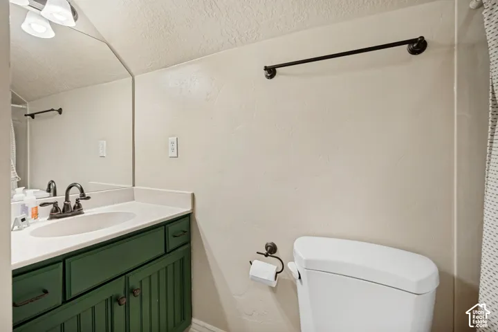 Bathroom featuring a green-finish vanity with a white countertop and oval undermount sink, dual-handle faucet, wall-mounted light fixture, and black hardware