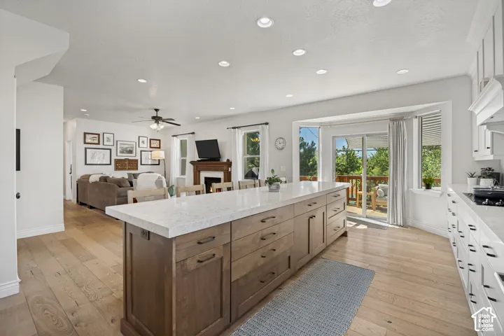 Kitchen featuring a large island with stone countertops, wood-finish cabinetry, recessed lighting, and wood-finish flooring